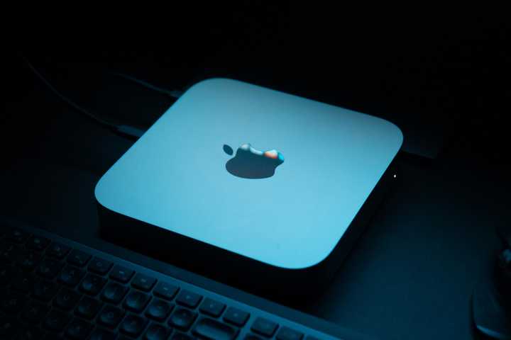 A Mac mini on a desk in a dark room under blue mood lighting.