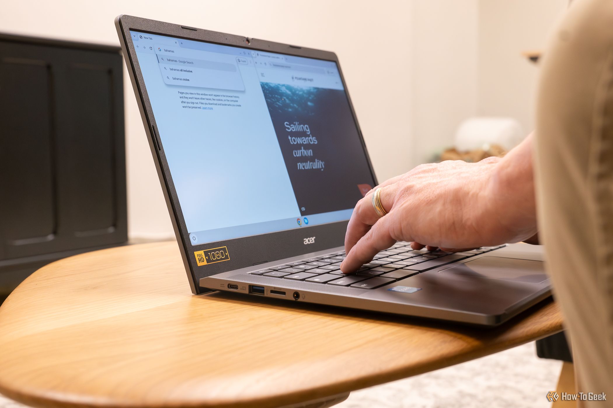An Acer Chromebook sitting on a table with someone typing on it.