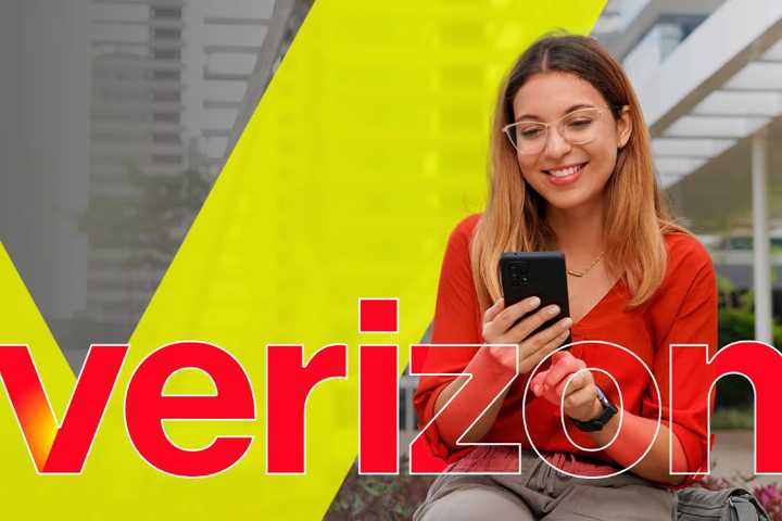 a-woman-sitting-on-a-bench-using-her-smartphone-with-the-verizon-logo-in-the-center