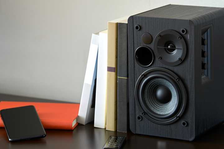 Bookshelf speaker with books and iPhone.