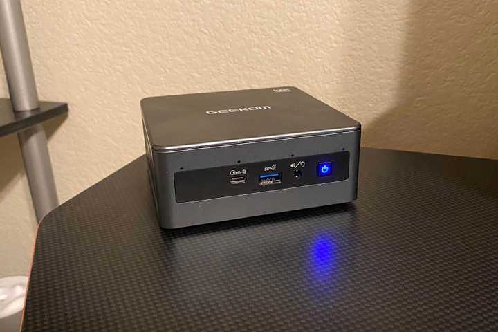GEEKOM Mini IT11 PC front-facing on a black desktop.