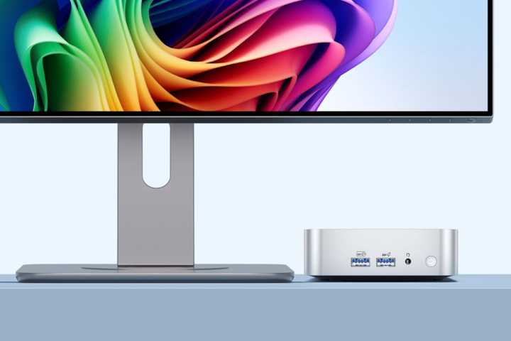 A GEEKOM A6 Mini PC sitting on a table connected to a monitor. 