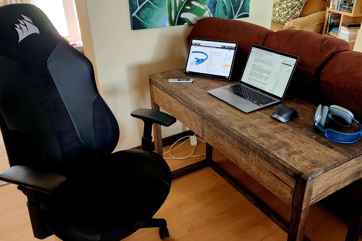 A desk With a MacBook and iPad next to some Airpods Max and an Apple TV Remote